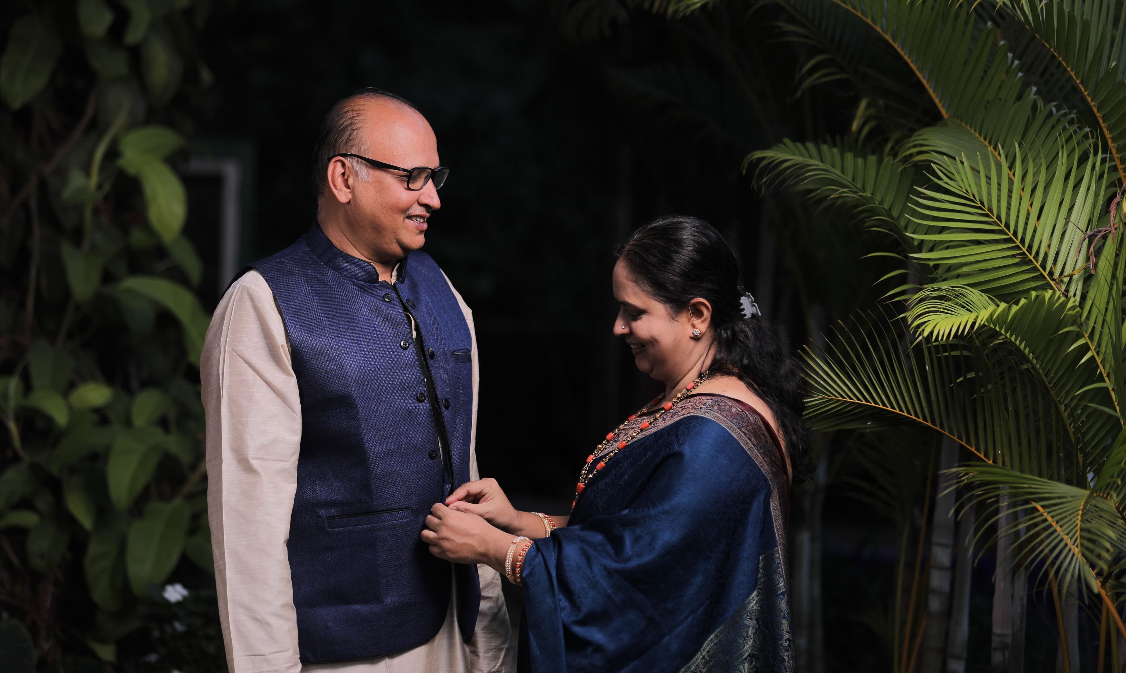 An elderly Indian couple sharing a warm moment in a garden in the evening