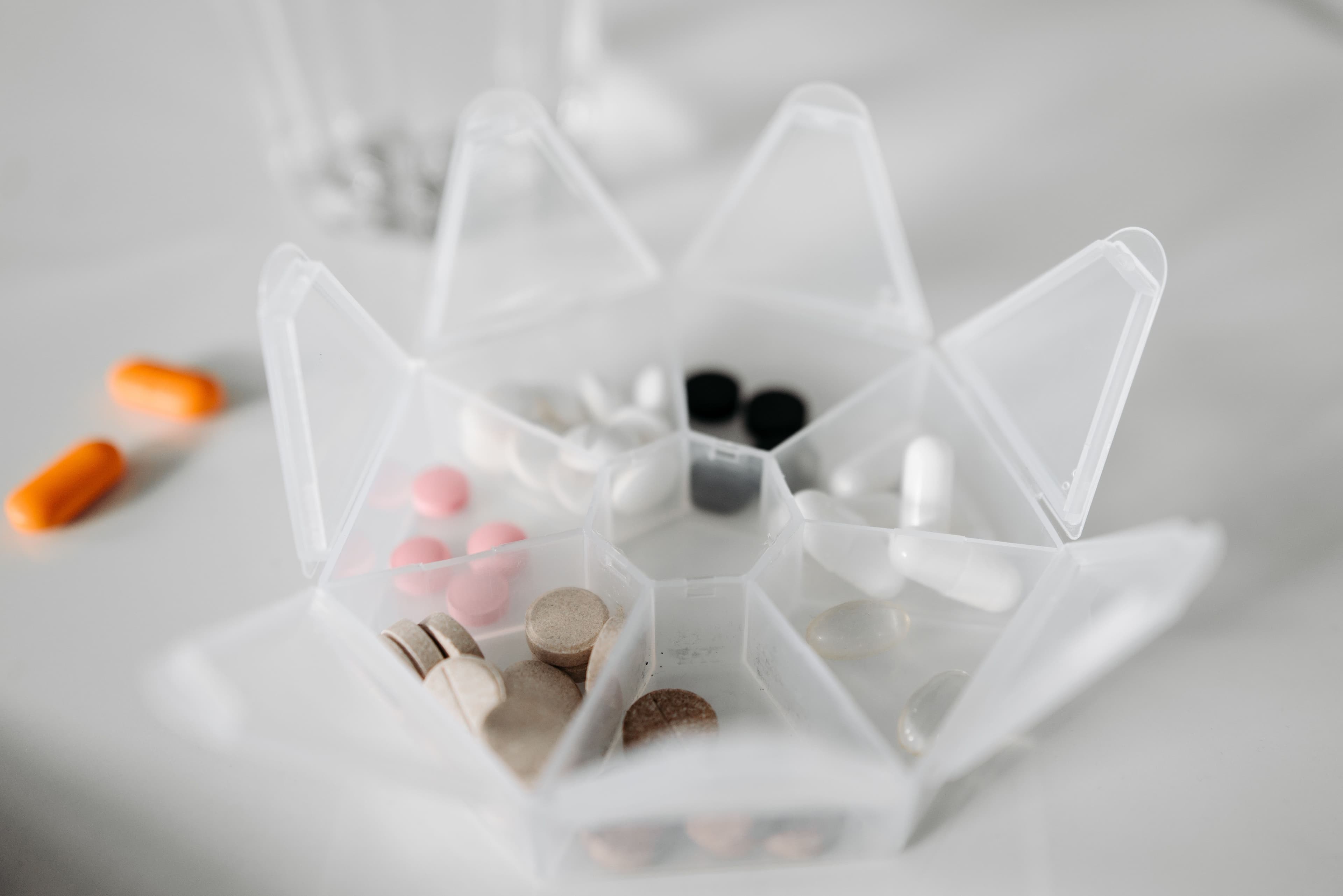 An open weekly pill organizer with several compartments left empty
